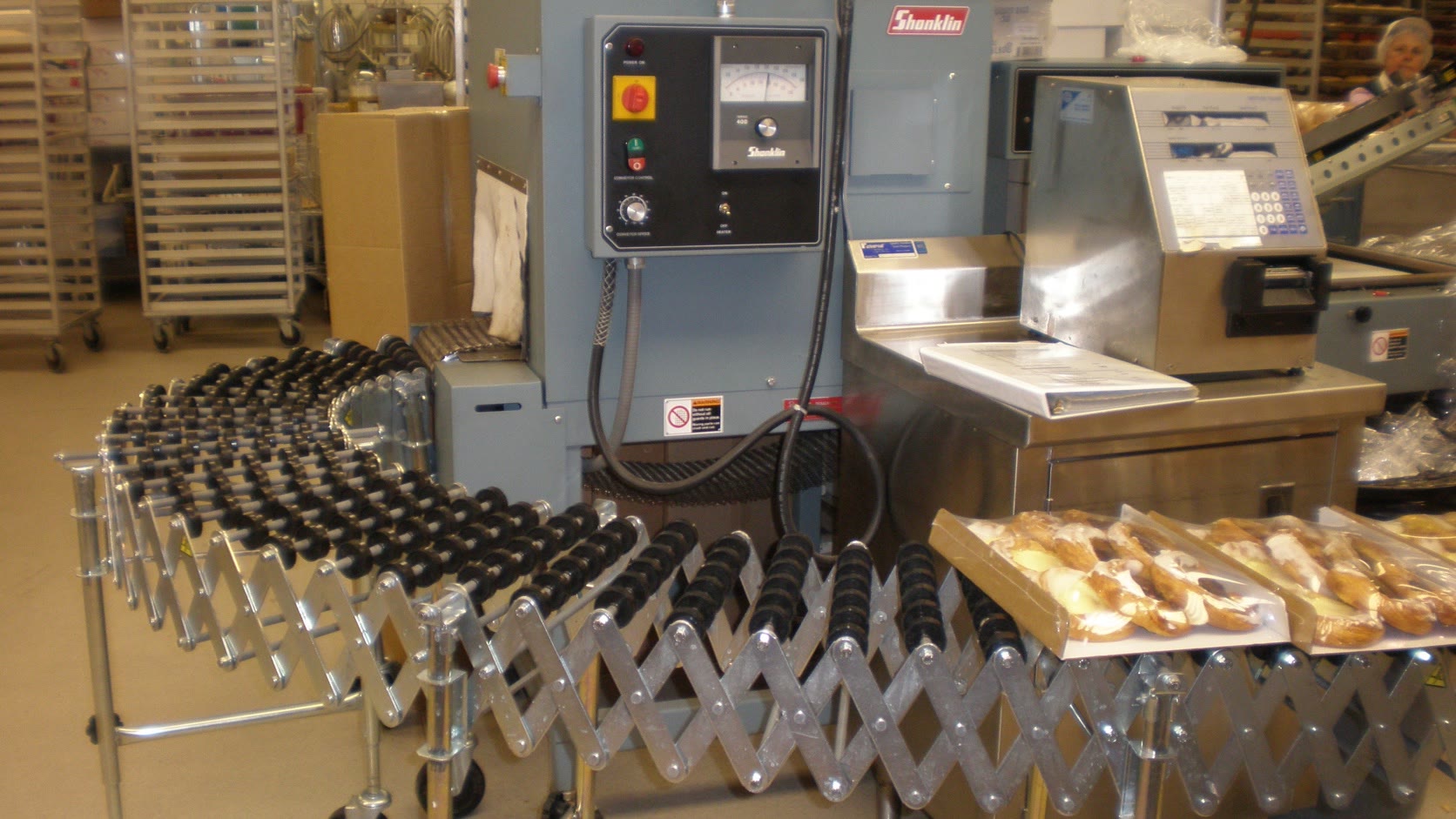 Real food packaging line with conveyors, wrapping equipment, controls, and production staff