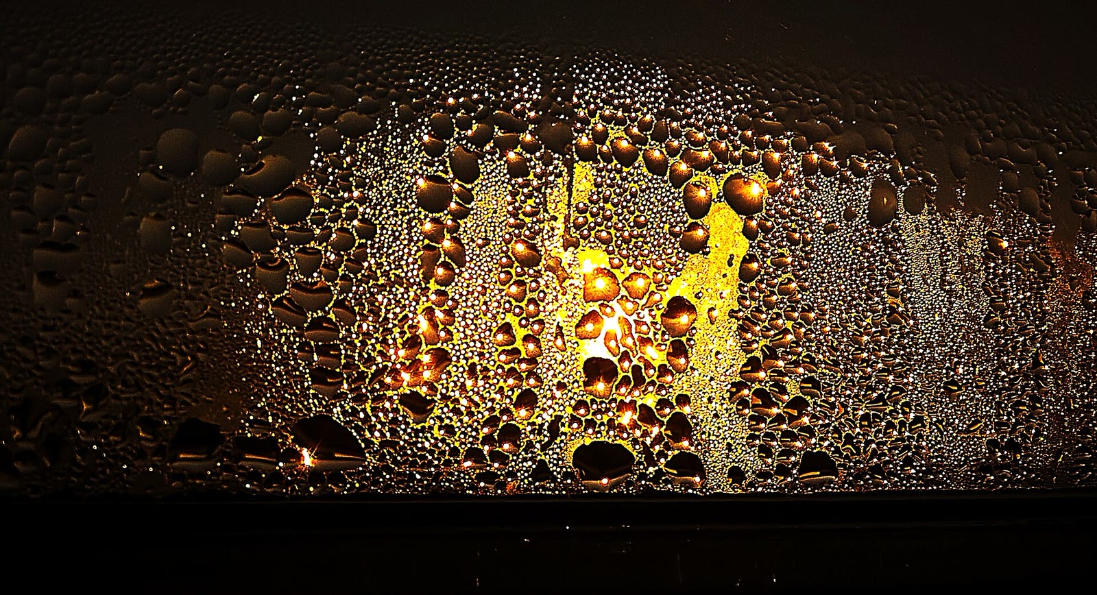 Real condensation droplets on window glass illuminated by sunset