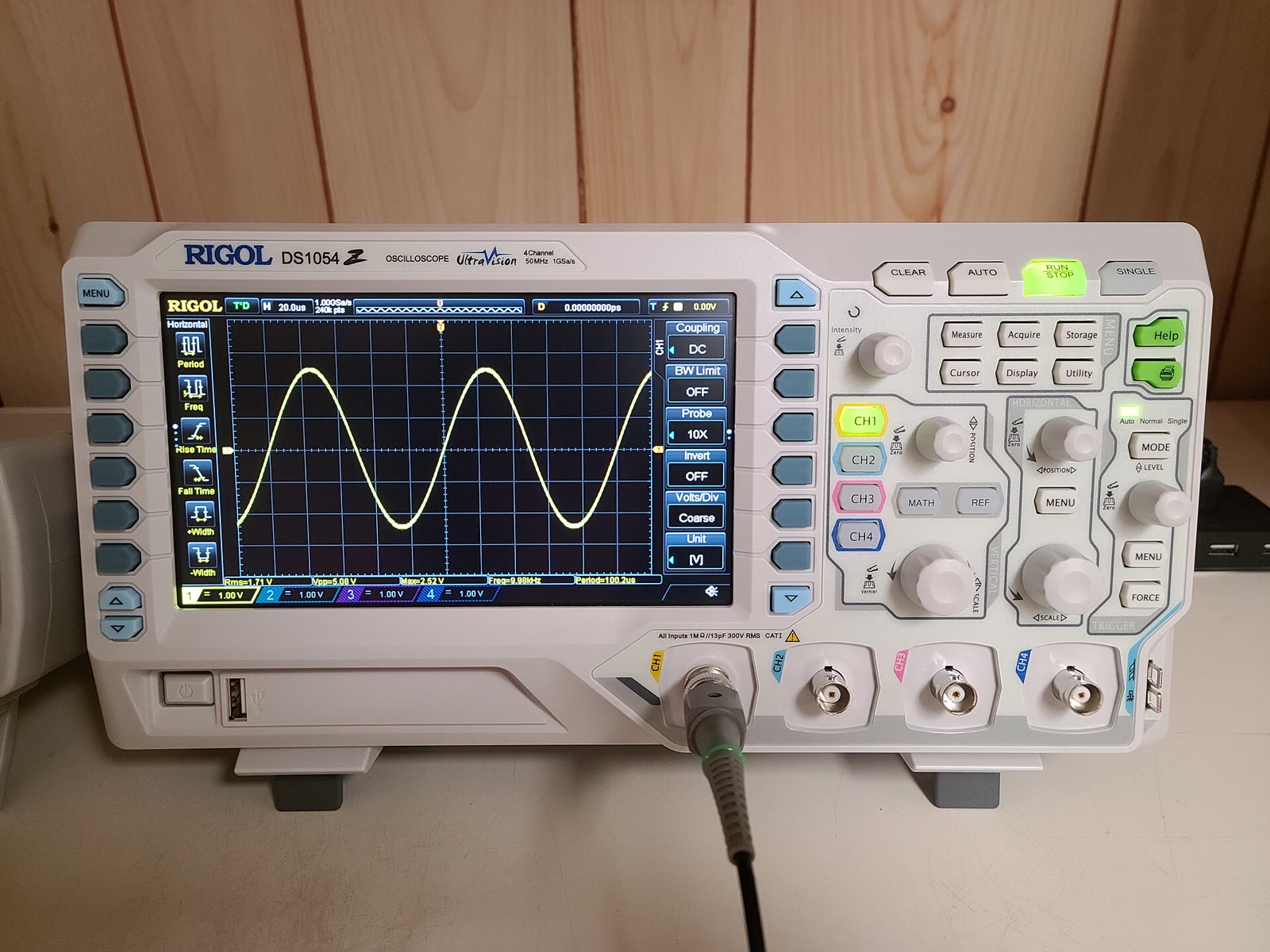 RIGOL digital storage oscilloscope showing a sine waveform with physical knobs and channel controls